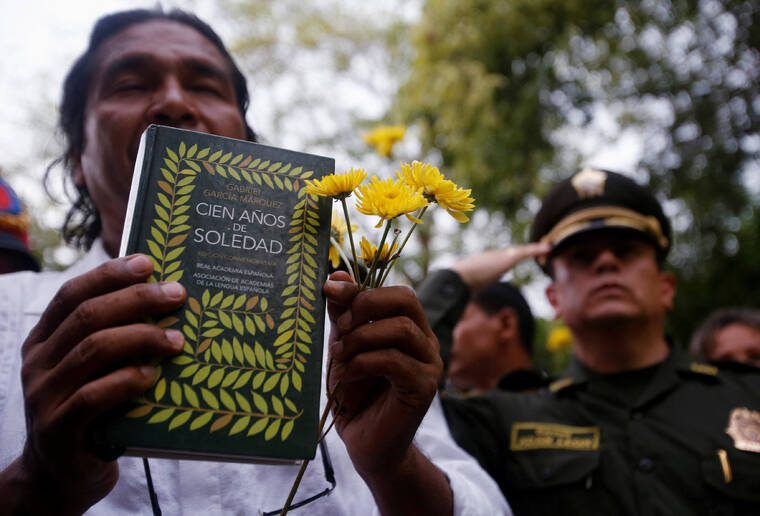 JOHN VIZCAINO /REUTERS
                                A resident holding flowers and a book “Cien Anos de Soledad” (One Hundred Years of Solitude) by Colombian Nobel laureate Gabriel Garcia Marquez takes part in a symbolic public funeral for Garcia Marquez, in Aracataca April 21, 2014.