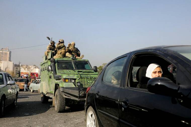 MAHMOUD HASSANO / REUTERS
                                Rebel fighters ride a military vehicle Monday after they seized the capital and ousted President Bashar al-Assad, in Damascus, Syria.