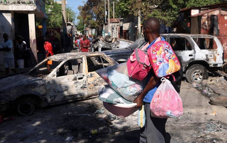 REUTERS/RALPH TEDY EROL
                                A man carrying his belongings observes the wreckages of vehicles burnt over the weekend by armed gangs, many grouped behind an alliance known as Viv Ansanm, as he flees the Poste Marchand suburb, in Port-au-Prince, Haiti, today.